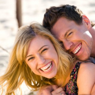 Happy couple embracing and laughing on the beach Happy couple embracing and laughing on the beach